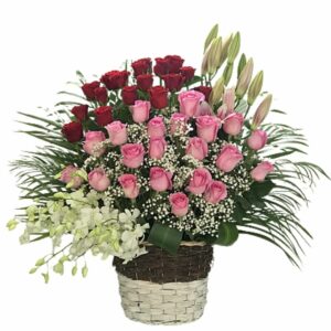 Roses, lilies and orchid are arranged in willow basket with suitable fillers